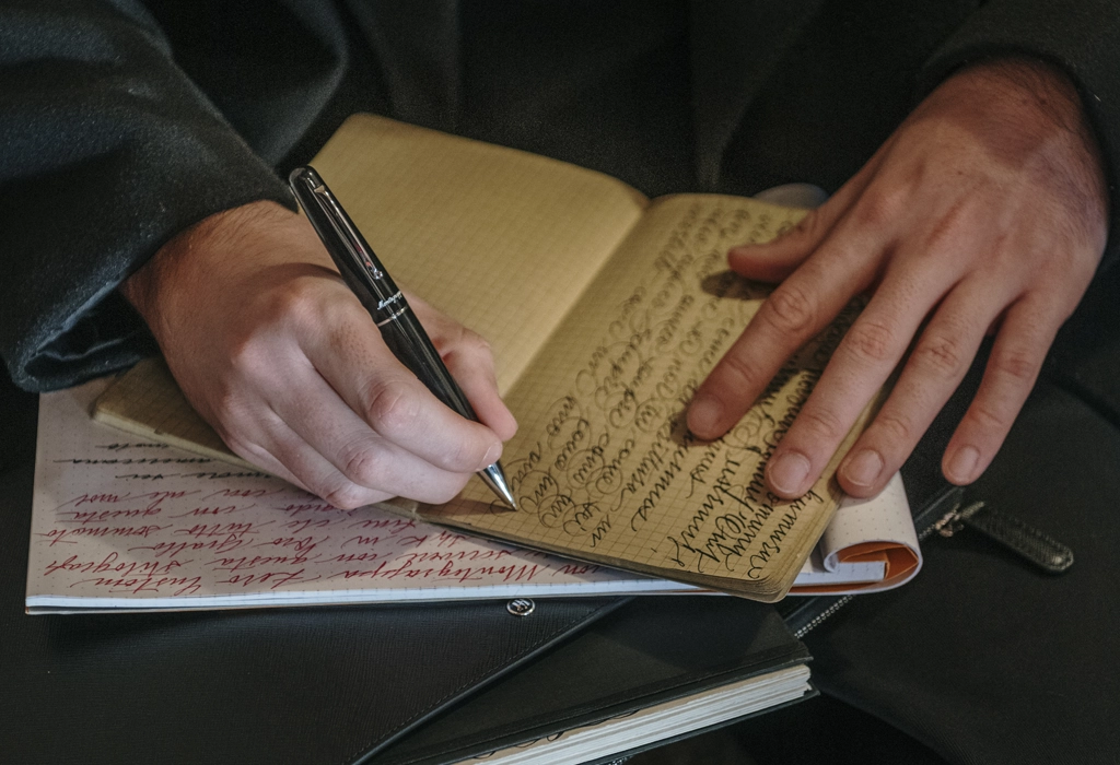 Stilou Elmo 01 folosit pentru scris de mână într-un caiet, accent pe gest, detaliu și experiență autentică, Luxury Grand Store